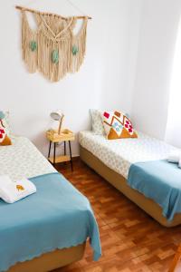 una camera con due letti e un lampadario a braccio di Vila Saudade a Costa da Caparica