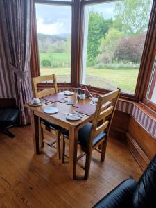 a wooden table in a room with a large window at Creag Meggan in Ballater