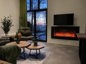 a living room with a fireplace and a tv at GREEN VILLA in bester Lage - Dachterrasse mit Meerblick - großer eingezäunter Garten - kinderfreundlich - Hunde inklusive - 4 Sterne Resort - direkt am Strand - Pool inklusive in Hulshorst