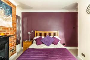 a bedroom with purple walls and a bed with purple pillows at Camaraderie Guest House in York