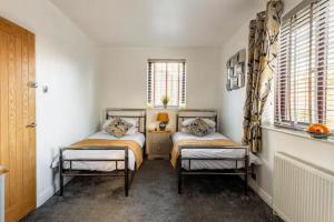 - 2 lits dans une chambre avec 2 fenêtres dans l'établissement Camaraderie Guest House, à York