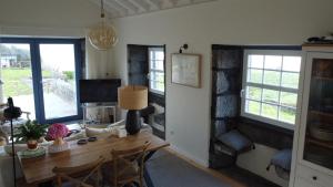 a dining room with a table and two windows at Casa da Ribeirinha in Ribeirinha