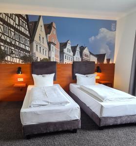 two beds in a room with a mural of buildings at EuroHotel Günzburg in Günzburg