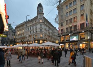 grupa ludzi chodzących po mieście z wieżą zegarową w obiekcie Kaiserin Sissi - City Apartment Downtown Vienna w Wiedniu