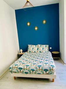 - une chambre dotée d'un lit avec un mur bleu dans l'établissement Le Moderne, à Issoudun