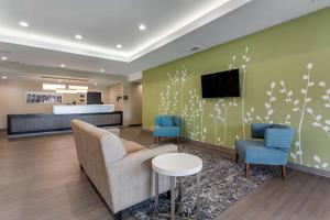 een lobby met twee stoelen en een tv aan de muur bij Sleep Inn & Suites in Crosby