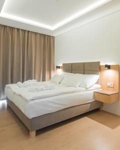 een slaapkamer met een groot bed met witte lakens bij H55 in Balatonlelle