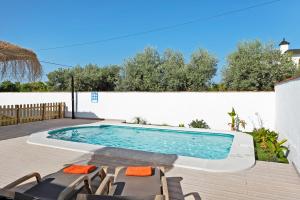 ein Pool auf einer Terrasse neben einer weißen Wand in der Unterkunft Casa Villanueva 1 -sólo Familias in Hozanejos