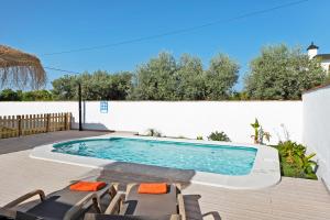 a swimming pool on a deck next to a white wall at Casa Villanueva 1 -sólo Familias in Conil de la Frontera