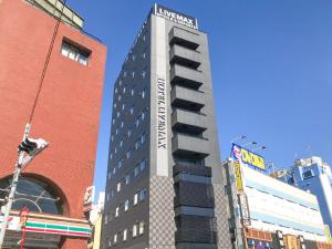 un edificio alto con un cartello dell'hotel sopra di HOTEL LiVEMAX Chiba Chuo-Ekimae a Chiba