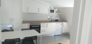 a kitchen with white cabinets and a table and chairs at APARTAMENTOS DON MANUEL B in Cee