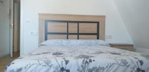 a bedroom with a bed with a blue and white comforter at APARTAMENTOS DON MANUEL B in Cee