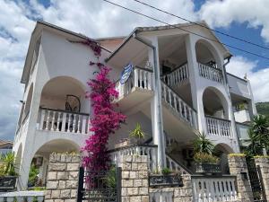 a white house with flowers on the side of it at Apartmani Tamara in Tivat