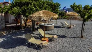 - un groupe de chaises longues et de parasols sur une plage dans l'établissement G & M Beach House, à Haraki