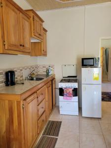 cocina con armarios de madera y nevera blanca en Memories Cottage and Apartments en Buccoo