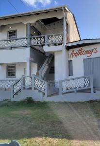 un edificio blanco con escaleras y un cartel en él en Memories Cottage and Apartments, en Buccoo