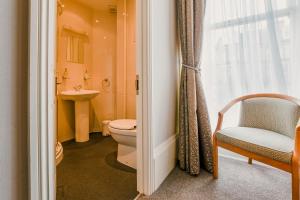 a bathroom with a toilet and a chair and a window at The Maynard in Scarborough