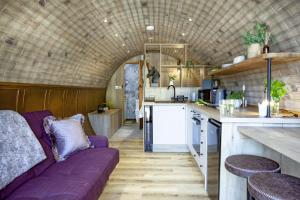 a living room with a purple couch in a kitchen at The Charm Inn, The Little Burrow, Nr Wells in Radstock