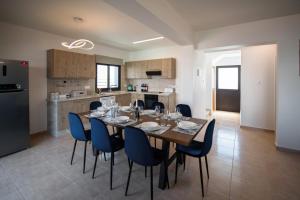 kuchnia i jadalnia ze stołem i niebieskimi krzesłami w obiekcie Luxury Villa Agathoula w mieście Protaras