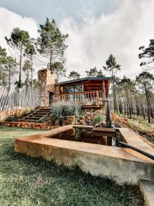 a log home with a deck and a house at Krakeelpoort Herberg in Botrivier