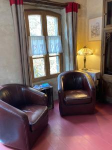 two leather chairs in a living room with windows at La cour secrète in Dinan