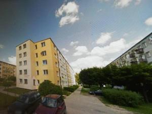 Ulica z dwoma budynkami i samochodem zaparkowanym obok niej w obiekcie Apartament Parkowy 2 pokojowy w mieście Mrągowo
