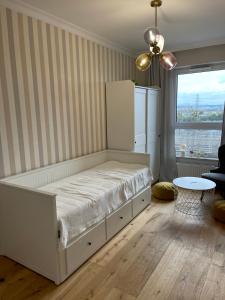 a white bedroom with a bed and a table at Sucha Street Apartments, Nowa Letnica,Gdańsk in Gdańsk