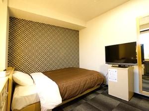a hotel room with a bed and a flat screen tv at HOTEL LiVEMAX Kyoto Gojo in Kyoto