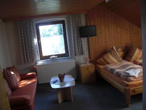 Schlafzimmer mit einem Bett, einem Tisch und einem Fenster in der Unterkunft Pension Wiesenau in Bayerisch Eisenstein