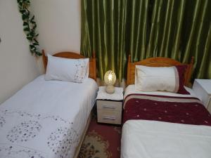 twee bedden in een kleine kamer met groene gordijnen bij CHARLES INN in Liverpool