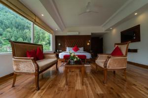 a hotel room with a bed and two chairs at The Allure Grand - Riverside Resort & Spa in Manāli