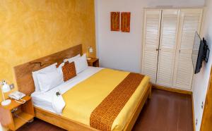 a bedroom with a large bed with a yellow blanket at La Villa Boutique Hotel in Accra