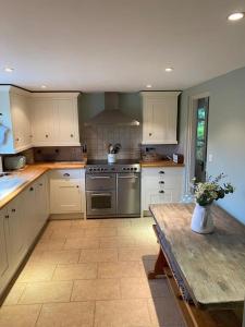 a kitchen with white cabinets and a wooden table at ‘The Nest’ A beautiful cottage in Devon in Axminster