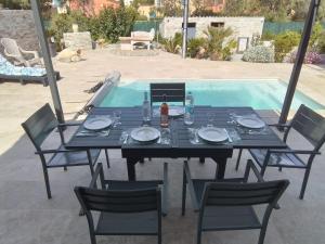 a black table with chairs and a table and a pool at Le Domaine De Marie in Palasca
