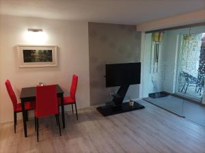 a dining room with a table and red chairs and a television at Green House 45 in Třebíč