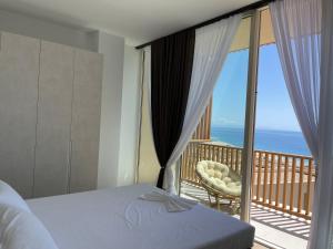 a bedroom with a bed and a balcony with the ocean at Green Coast 136 in Dhërmi
