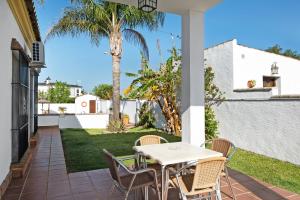 a patio with a table and chairs and a palm tree at Casa Villanueva 4 - Sólo Familias in Hozanejos