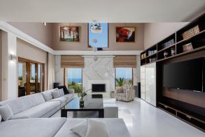 een woonkamer met een witte bank en een open haard bij Alpha Luxury & Spa Villa in Rethimnon