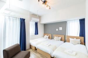 two beds in a room with blue curtains at Minn Umeda East in Osaka