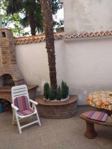a patio with two chairs and a table and a palm tree at Kuća za odmor Mery in Crikvenica