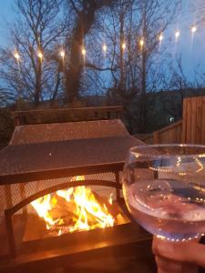 a person holding a glass of wine next to a fire at Birchwood Cottage - In the Heart of Wooler in Wooler