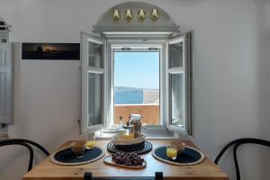 a table with plates of food and a window at Villa Oasis Oia with Caldera View in Oia