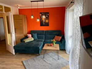 sala de estar con sofá verde y pared de color naranja en Landhotel Sportalm en Philippsreut