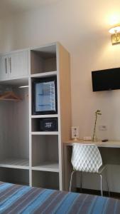 a room with a bed and a tv and a desk at Hotel Lucerna in Castiglione della Pescaia