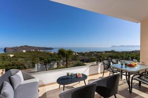 a balcony with chairs and tables and a view of the ocean at Villa Aretousa 2 in Agia Marina Nea Kydonias