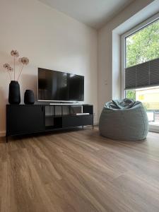 a living room with a flat screen tv and a ottoman at Apartmenthaus Stade Schwingewiesen Apartment 4 in Stade +7 photos