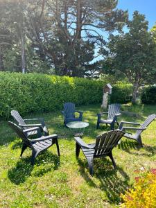 a group of chairs and a table in the grass at Grande maison familiale, à 600m de la plage de Tahiti in Névez