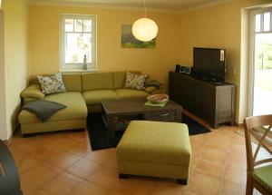 ein Wohnzimmer mit einem Sofa und einem TV in der Unterkunft Apartment Strandkate Wohnung Strandhafer in Börgerende-Rethwisch