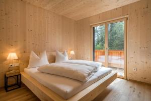 Un dormitorio con una cama con almohadas blancas y una ventana en Naturapartments Alpreid Feine, en San Pancrazio