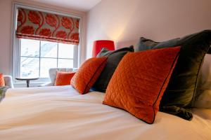 a bedroom with a bed with orange and black pillows at RHUBARB at Drapers Hall in Shrewsbury